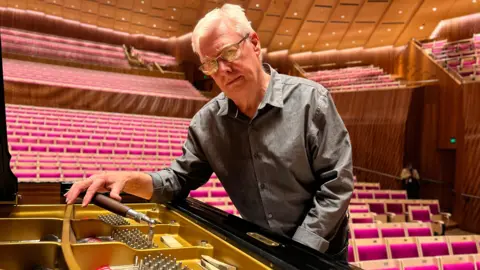 Terry Harper en pleine séance d’accord de piano dans la salle de concert
