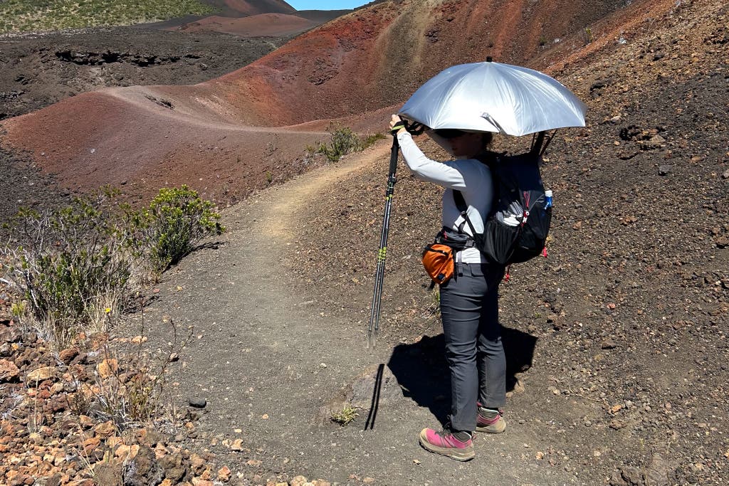 Personne utilisant un parapluie de randonnée sur un sentier