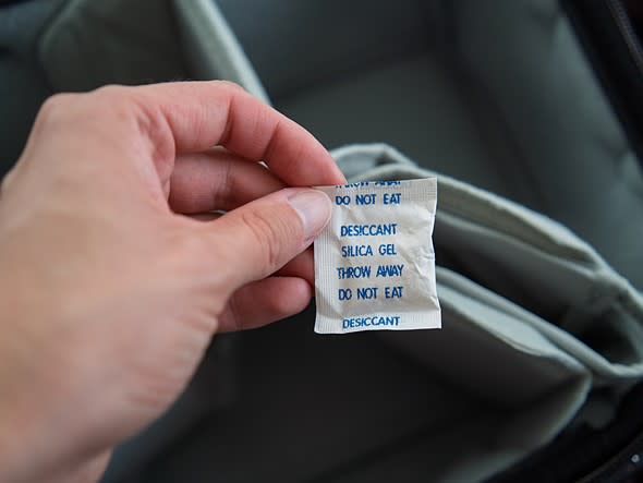 Un sachet de gel de silice tenu au-dessus d’un sac photo
