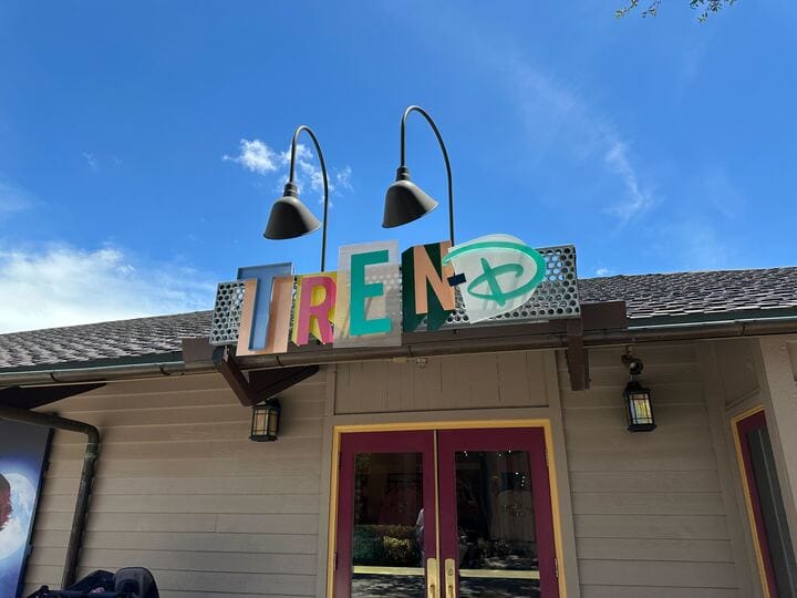 Enseigne colorée 'TrendD' inspirée d'Ursula et de la Méchante Reine suspendue à l’entrée d’une boutique