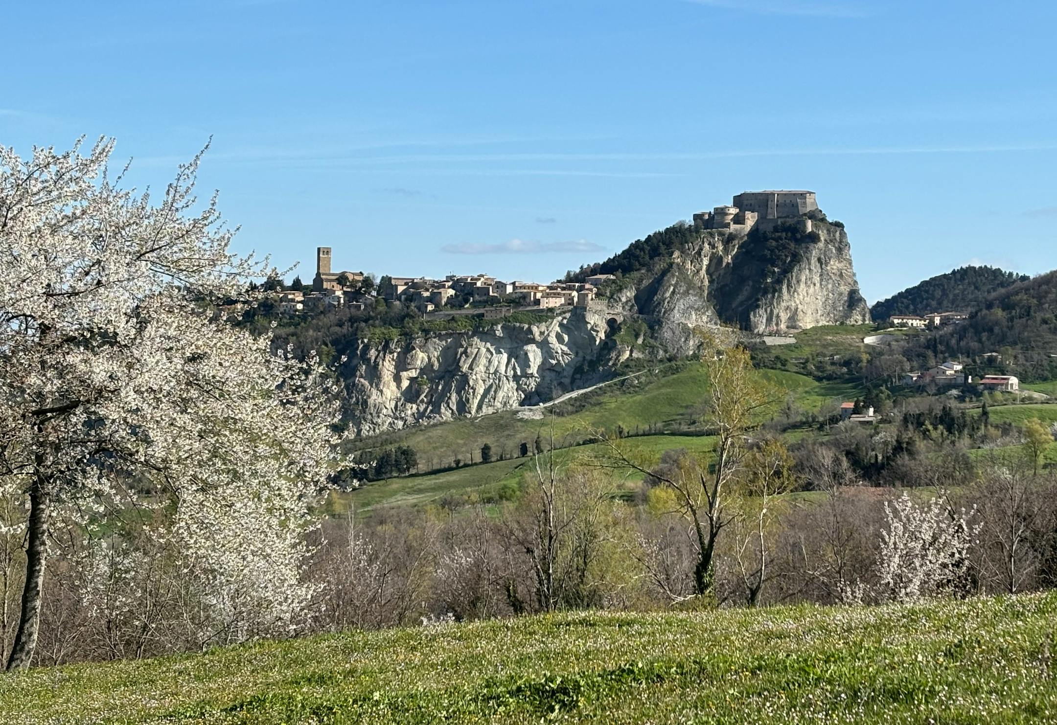 San Leo se dresse au loin, point d’ancrage visuel pour les randonneurs lors du trek de 11 jours 'Sur les pas de Saint François' organisé par Esperienza.